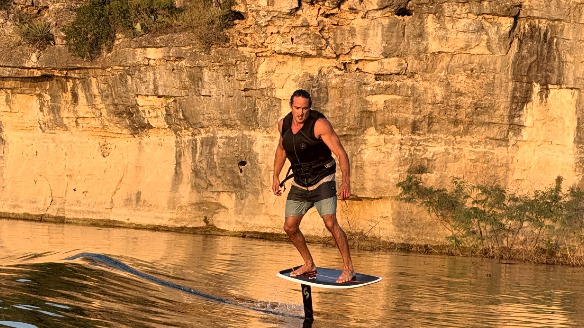 Jeff Halvordson hydrofoiling at golden hour in front of a limestone cliff