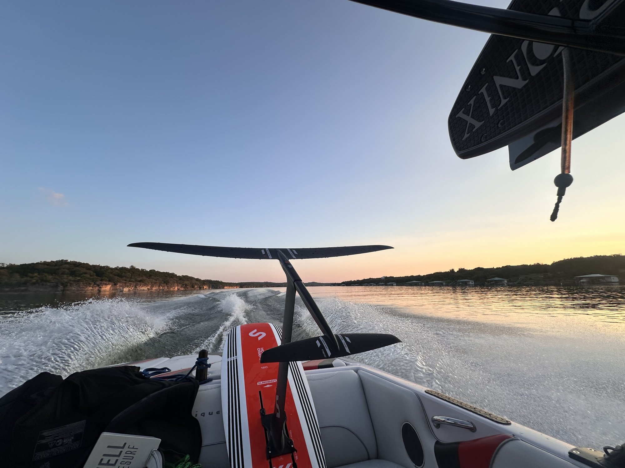 Slingshot hydrofoil board and black mast at the stern of a boat at sunset